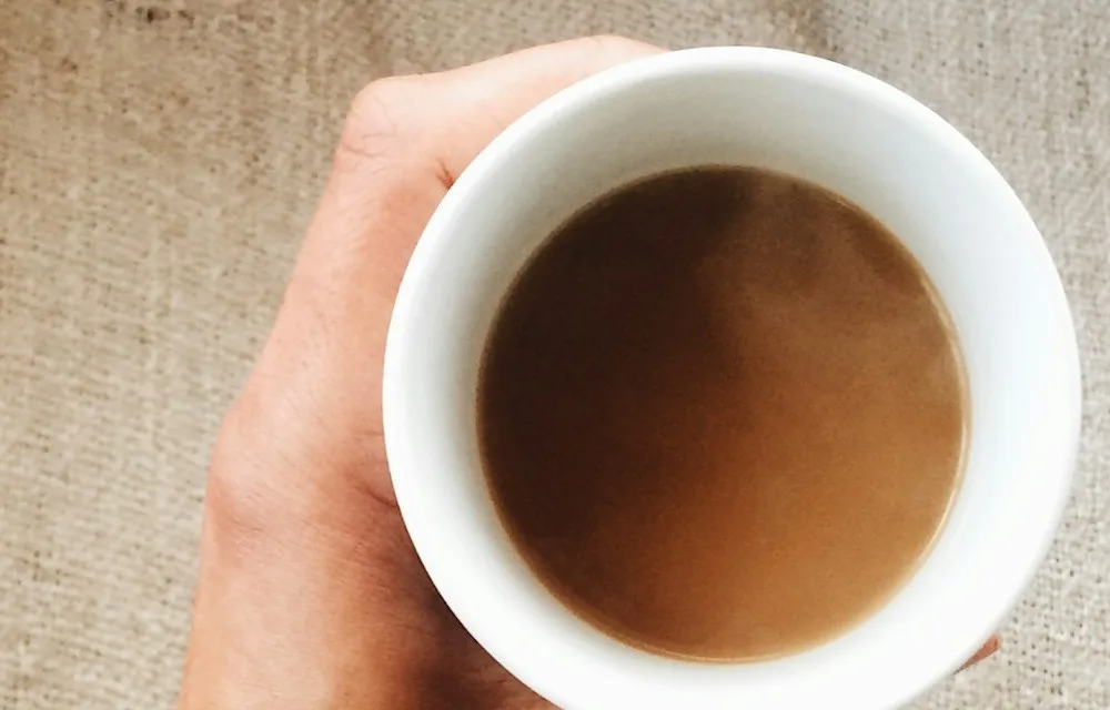 Une main tenant une tasse chaude, vue de dessus